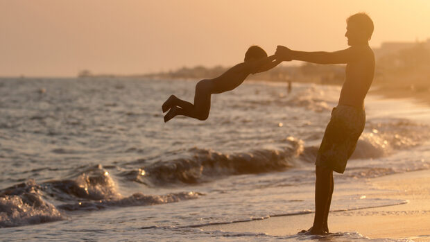far og søn i aftensol på strand